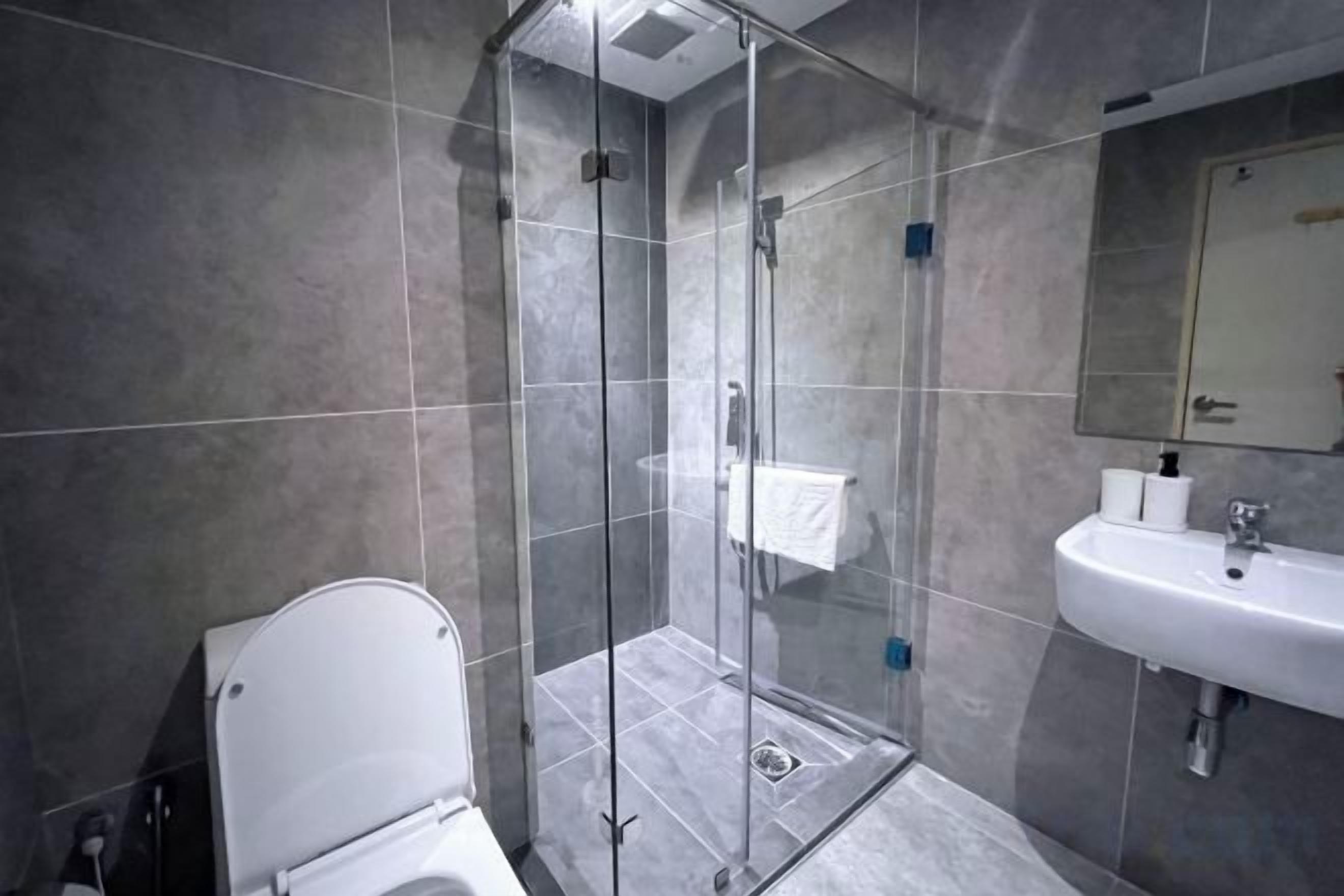 A modern bathroom with a glass shower enclosure, a white toilet, and a sink with a mirror above it.