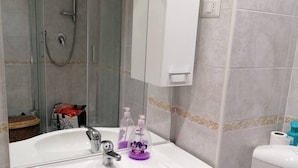 Ein Badezimmer mit einem weißen Waschbecken, einem Spiegel und einer Duschkabine.