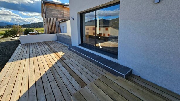 A modern building with a wooden deck and a large sliding glass door.