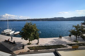 A waterfront promenade with boats docked, trees, and people walking. - Romantic Benaco Sal - App 01 (Salò)