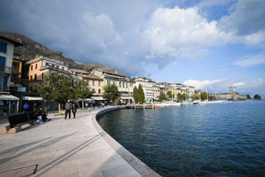 A waterfront promenade with buildings, a curved walkway, and a calm body of water. - Romantic Benaco Sal - App 01 (Salò)