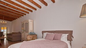 A bedroom with a large bed, wooden ceiling beams, a wardrobe, a chandelier, and a lamp. - Romantic Benaco Sal - App 01 (Salò)