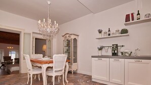 A dining area with a chandelier, white furniture, and a cabinet with wine bottles. - Romantic Benaco Sal - App 01 (Salò)