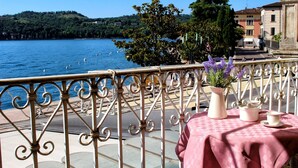 A balcony with a table set for two, overlooking a body of water with boats and a distant hill. - Romantic Benaco Sal - App 01 (Salò)