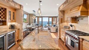 A spacious kitchen with a large island, granite countertops, and a view of the ocean.