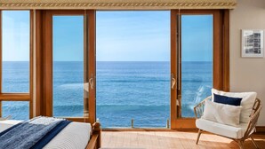 A bedroom with a large sliding glass door leading to a balcony with a sea view.