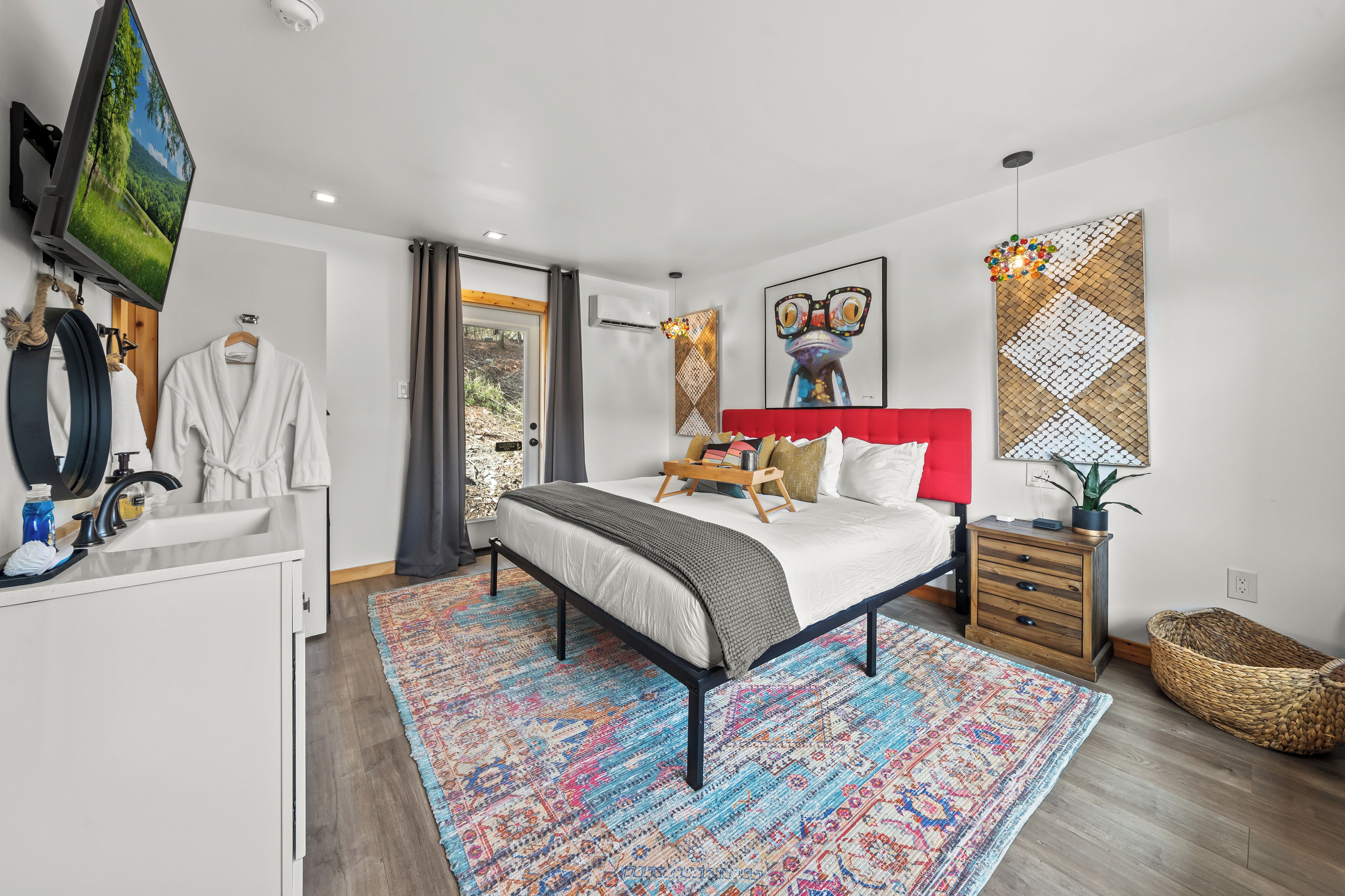 A modern bedroom with a bed, bedside table, TV, and a large window.