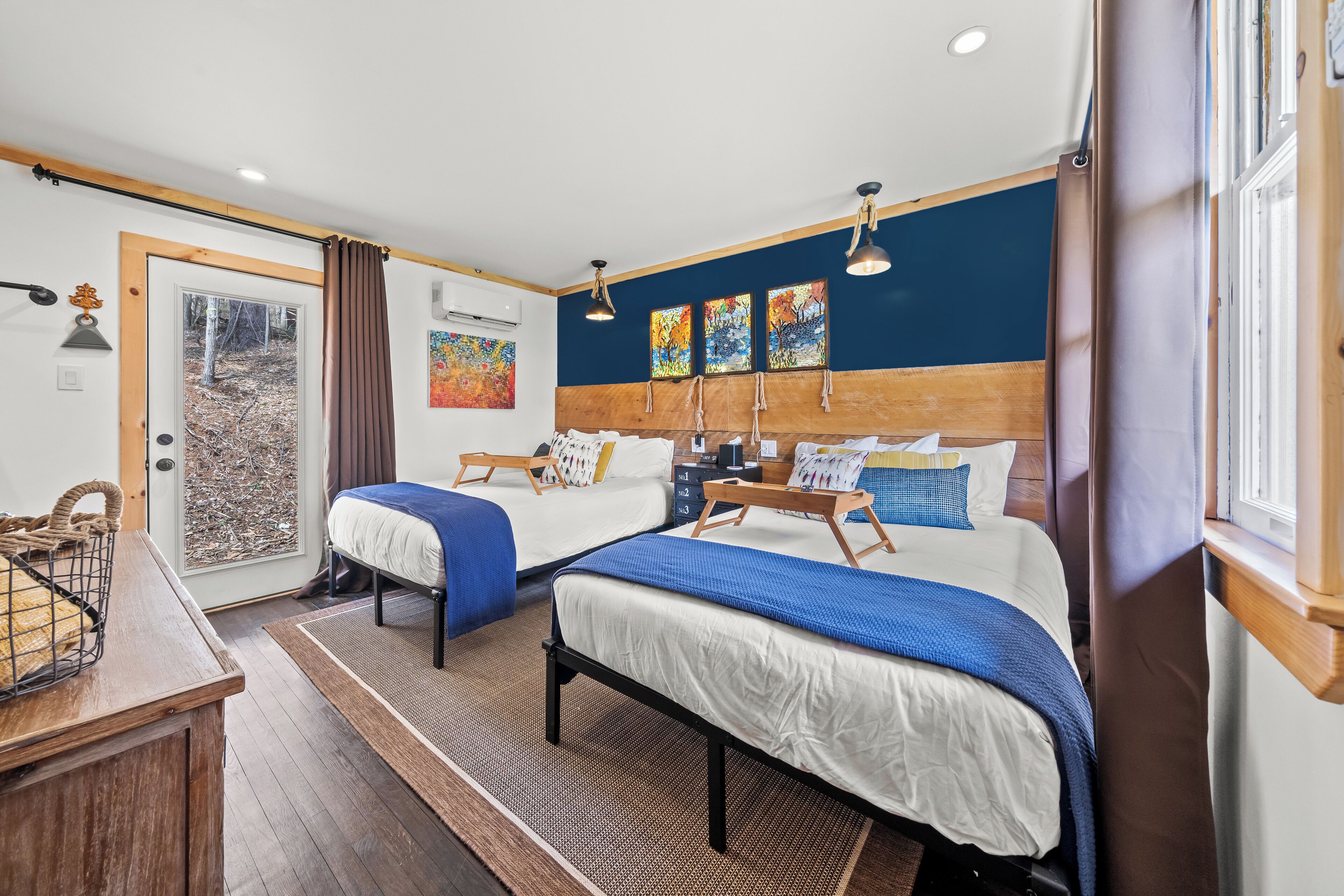 A bedroom with two beds, a wooden headboard, and a window with curtains.