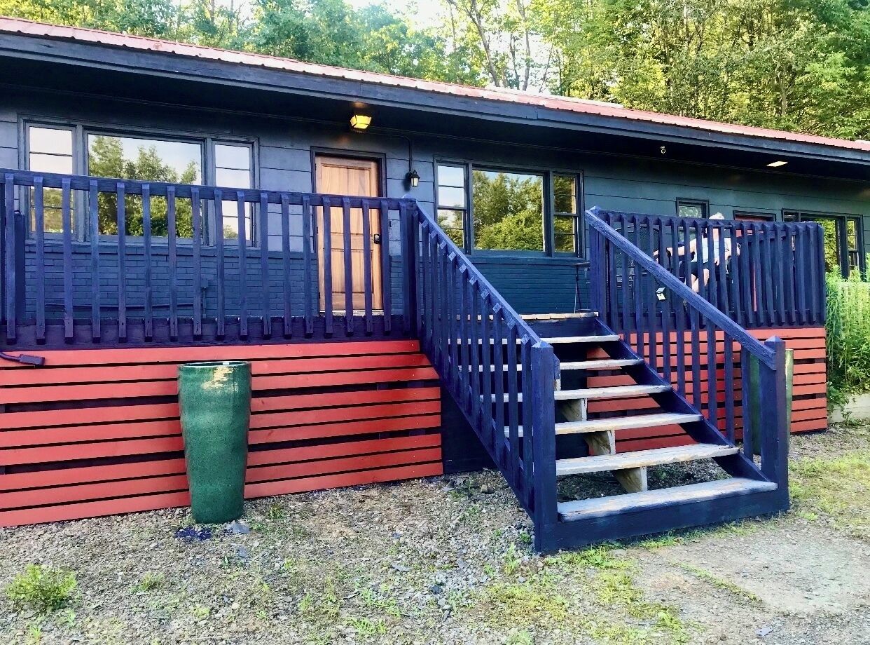 Un edificio con fachada roja, una escalera de madera y una valla de metal.