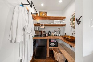 A compact kitchen with a black refrigerator, wooden shelves, a wooden countertop, a sink, and a decorative deer head.
