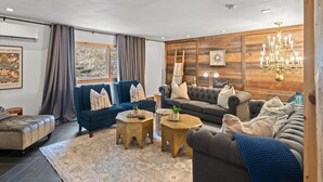 Una sala de estar moderna con un sofá seccional, un sillón azul y dos mesas de centro redondas.