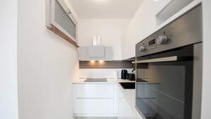 A modern kitchen with white cabinetry, a built-in oven, and a coffee maker.