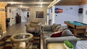 A cozy living room with a pool table, comfortable seating, and a billiards area.