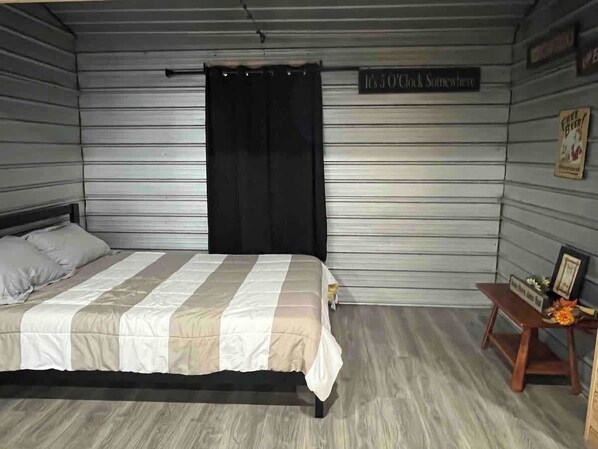 Een slaapkamer met een bed, nachtkastje en een bord aan de muur.