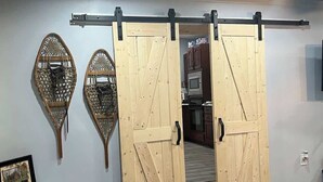 A room with a sliding barn-style door, a wooden bench, and a wall-mounted rack.