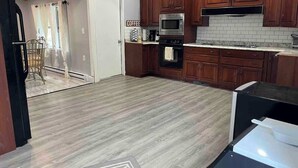 A modern kitchen with wooden cabinets, a microwave, and a coffee machine.
