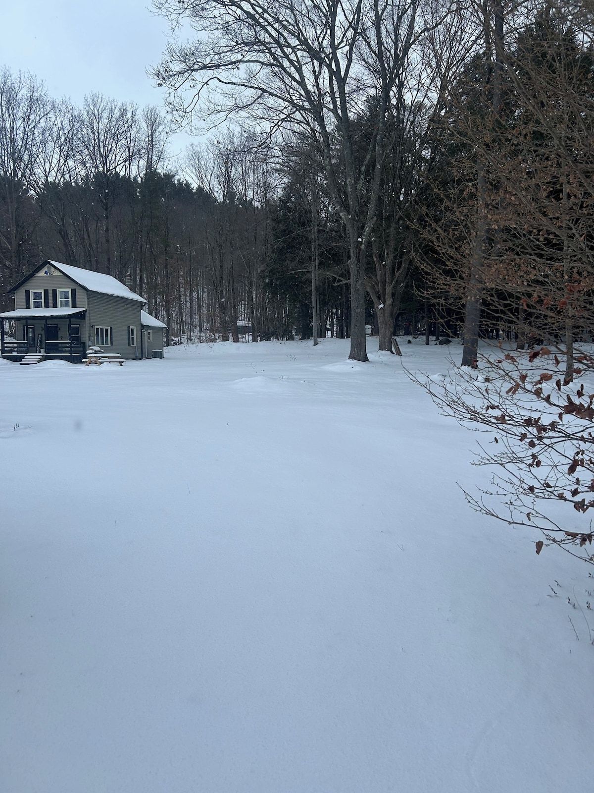 Una casa de dos pisos con un porche y un patio cubierto de nieve.
