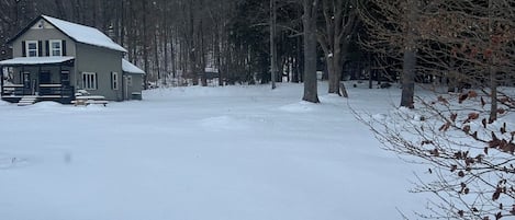 Una casa de dos pisos con un porche y un patio cubierto de nieve.