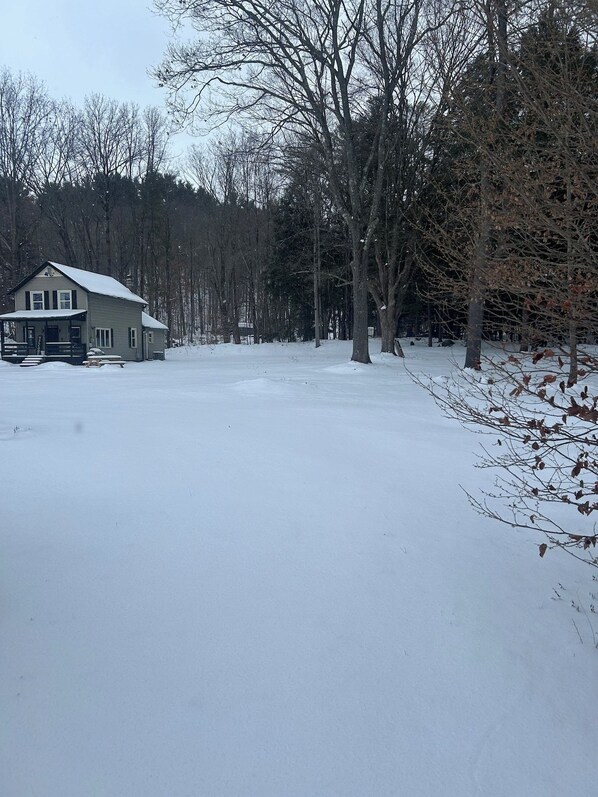 Una casa de dos pisos con un porche y un patio cubierto de nieve.