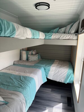 Une chambre avec un lit superposé, un plafond en pente et un puits de lumière.