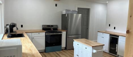 A modern kitchen with white cabinetry, stainless steel appliances, and wooden flooring.