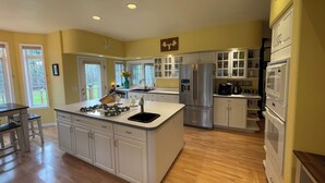 A spacious kitchen with a large island, white cabinetry, and stainless steel appliances. - “Wake Up by the Lake — Private Alaska Stay Near Hiking & ATV Trails” (seward)