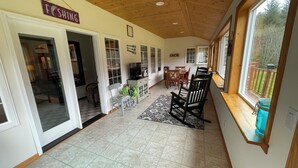 A spacious living area with a wooden ceiling, a dining table with chairs, a television, and a sign that reads "FISHING". - “Wake Up by the Lake — Private Alaska Stay Near Hiking & ATV Trails” (seward)