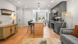A modern kitchen with grey cabinets, a central island, and stainless steel appliances.
