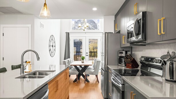 A modern kitchen with stainless steel appliances, a central island, and a dining area with a view of mountains.