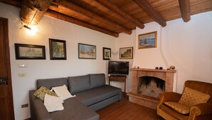 Una sala de estar con un sofá gris, una silla de madera, una chimenea y varias fotografías enmarcadas en la pared.