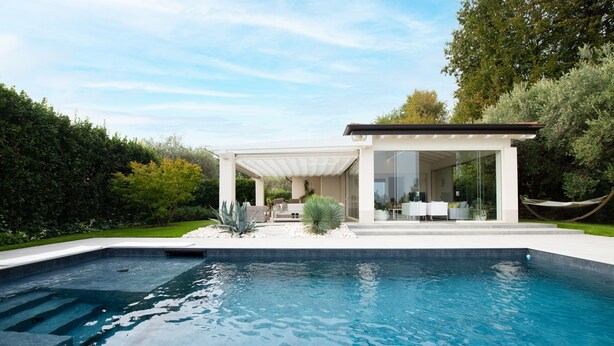 Uma casa moderna com piscina, varanda coberta e rede.