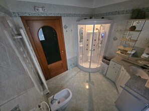 Un baño con cabina de ducha, lavamanos e inodoro.