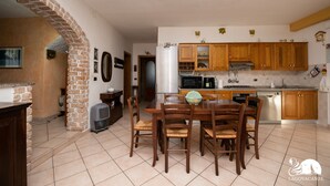 A kitchen with wooden cabinets, a dining table with chairs, and a refrigerator. - Casa Celestina in Padenghe sul Garda (Padenghe sul Garda)