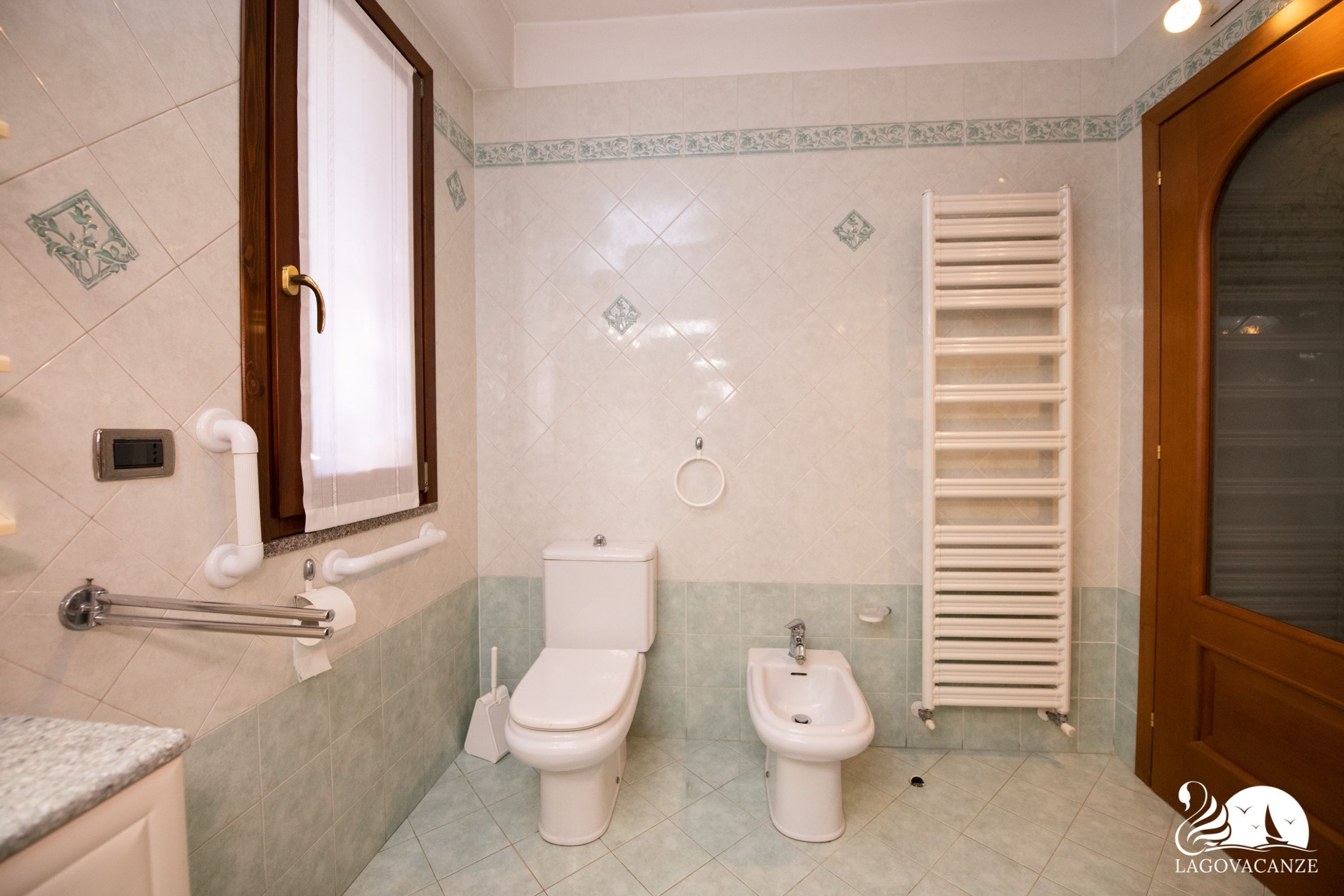 A bathroom with a toilet, bidet, towel rack, and a shower area.