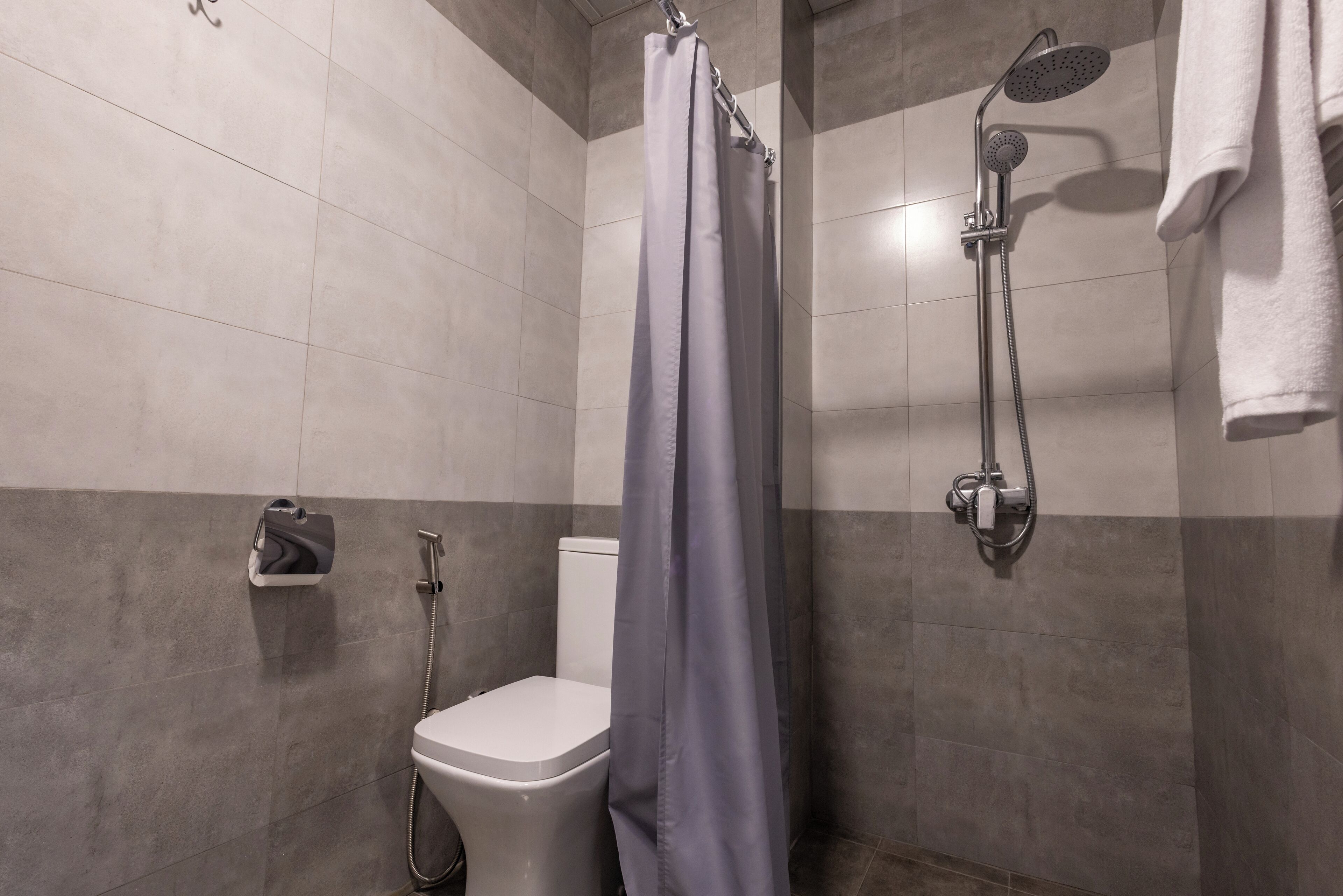 Un baño moderno con ducha, inodoro y barra para toallas.