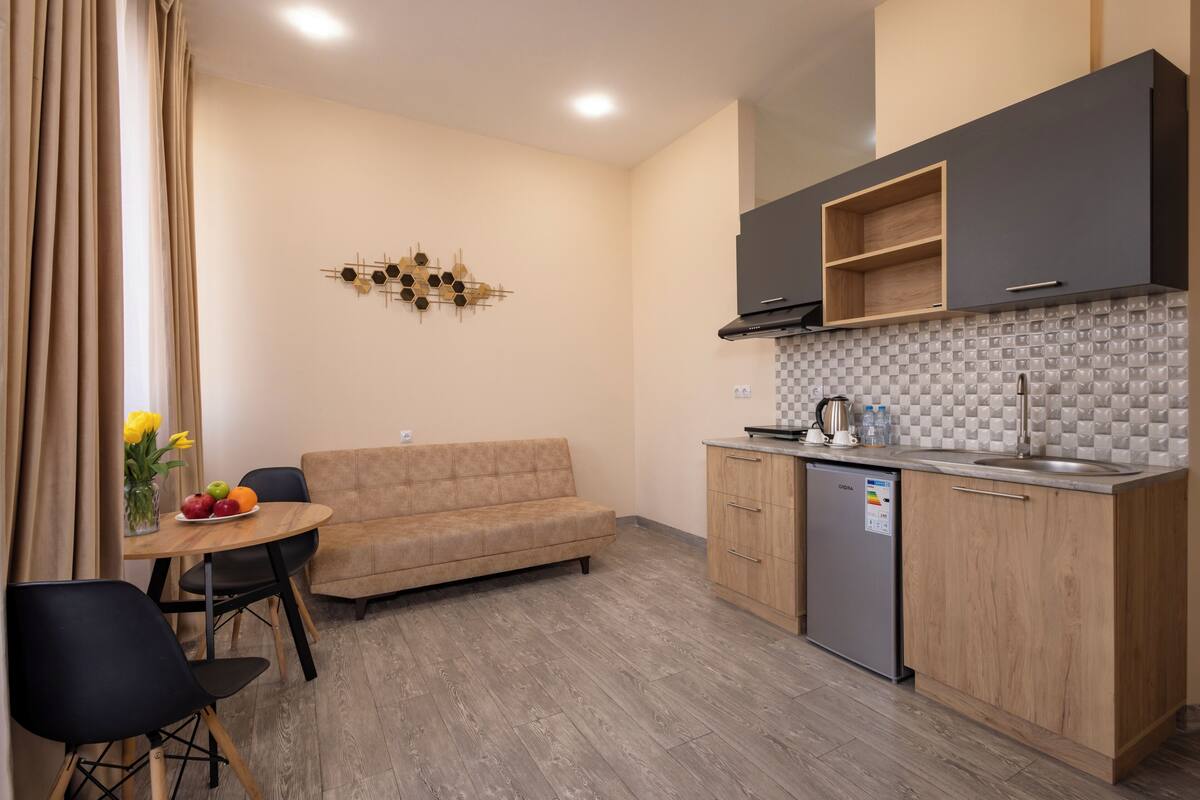 A compact kitchen with a dining area, a sofa, and a dishwasher.