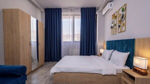 A bedroom with a large bed, a wardrobe, a nightstand with a lamp, and a view through the window. - Horizon Hotel Yerevan (Yerevan)