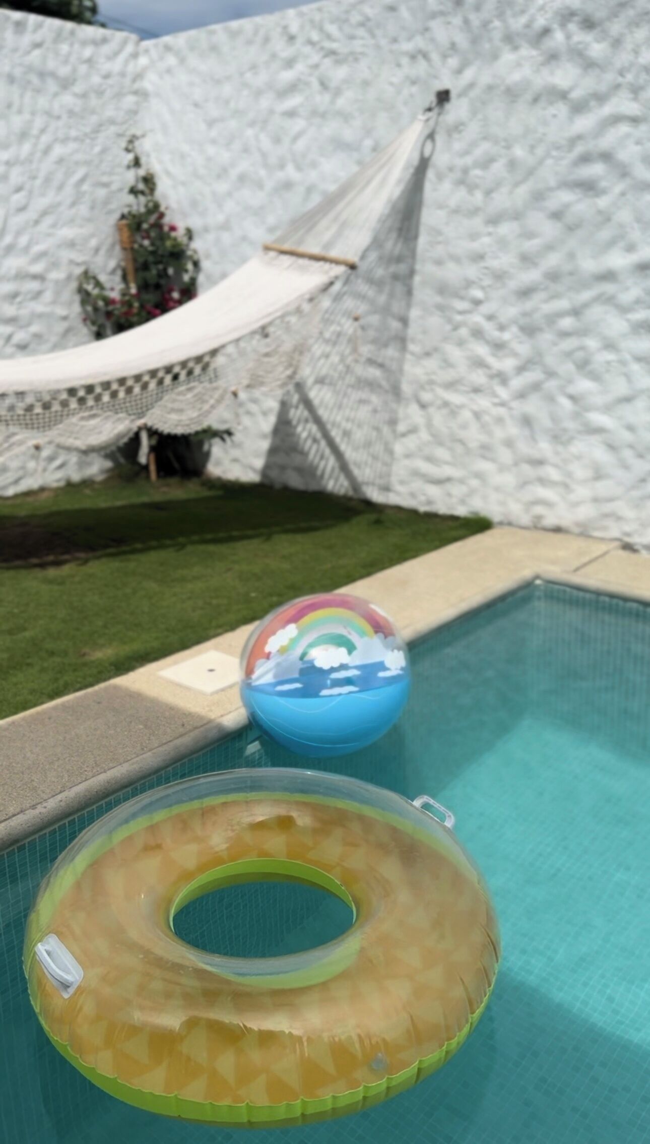 A swimming pool with a floating ring and a beach ball.