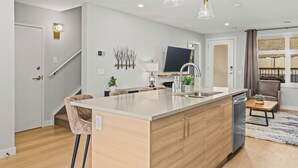 A modern kitchen with a central island, built-in appliances, and a dining area with a sofa and table.