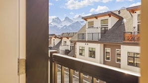 A view from a balcony overlooking a row of modern buildings with a mountain backdrop.