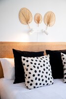 Una cama con ropa de cama blanca y almohadas a lunares negros y blancos.
