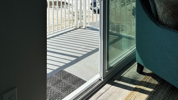 A room with a sliding glass door leading to a balcony with a view of the beach and ocean. - Surfside #11, Beautiful Beachfront Luxury Condo,  Allergy Friendly:No Pets. (Mexico Beach)