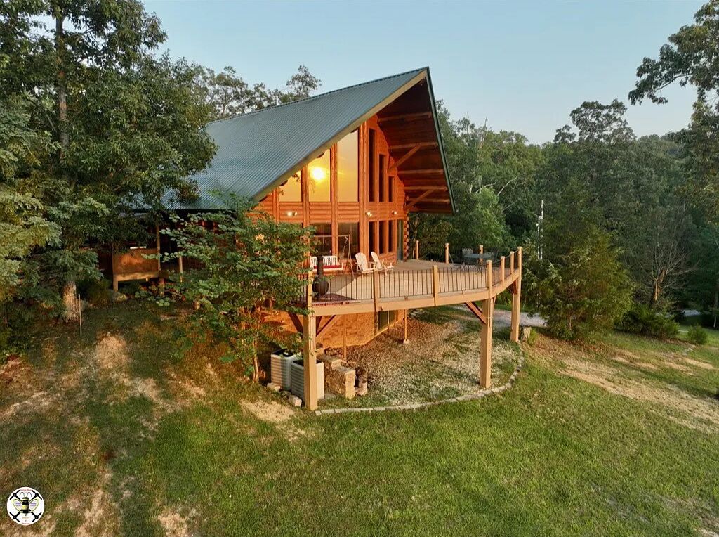 A wooden cabin with a sloped roof, a deck, and a large window.