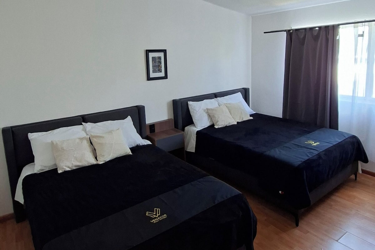 Two single beds with dark headboards and white bedding in a room with wooden flooring and a white ceiling.