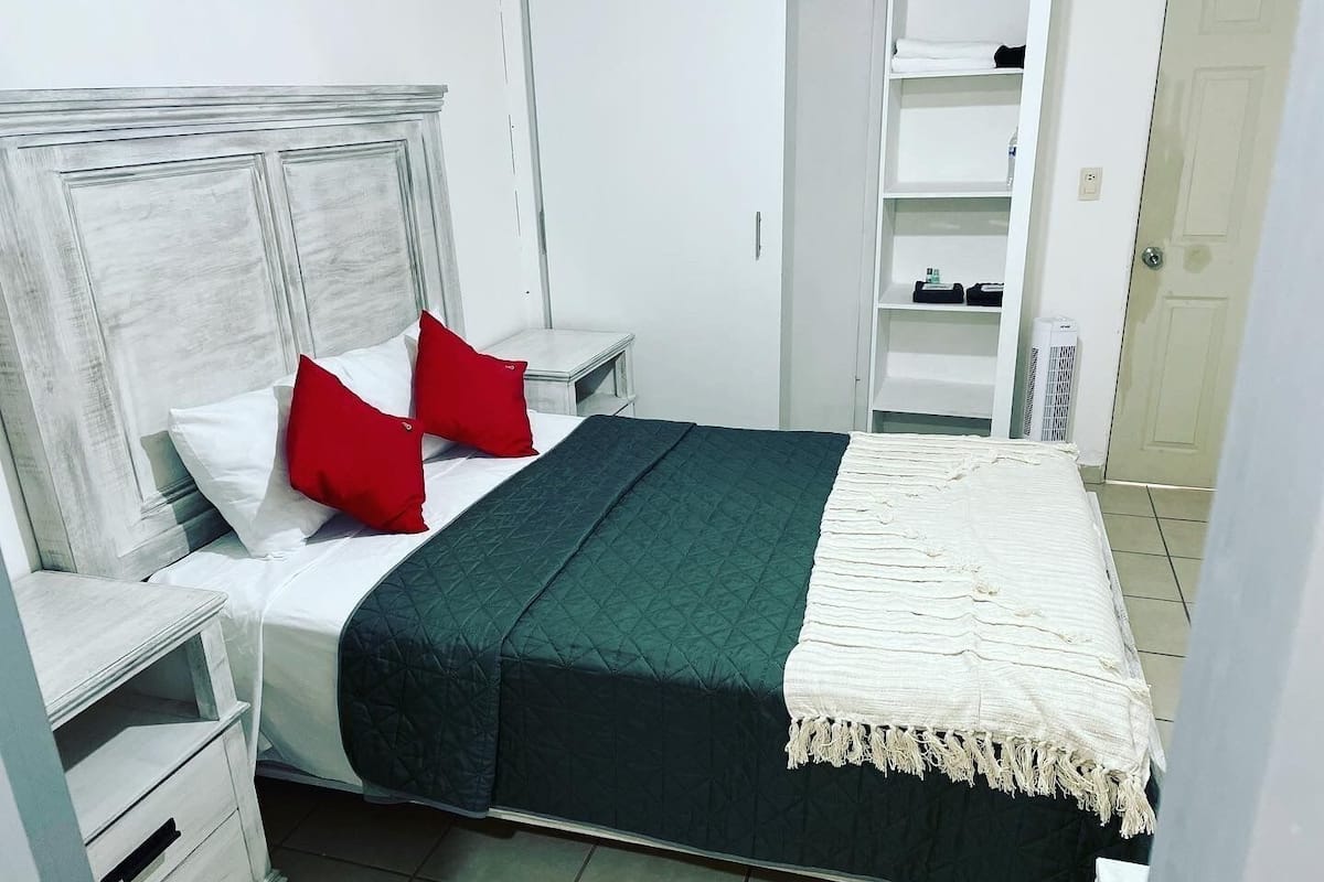 A neatly arranged bedroom with a bed, nightstands, a wardrobe, and a door.