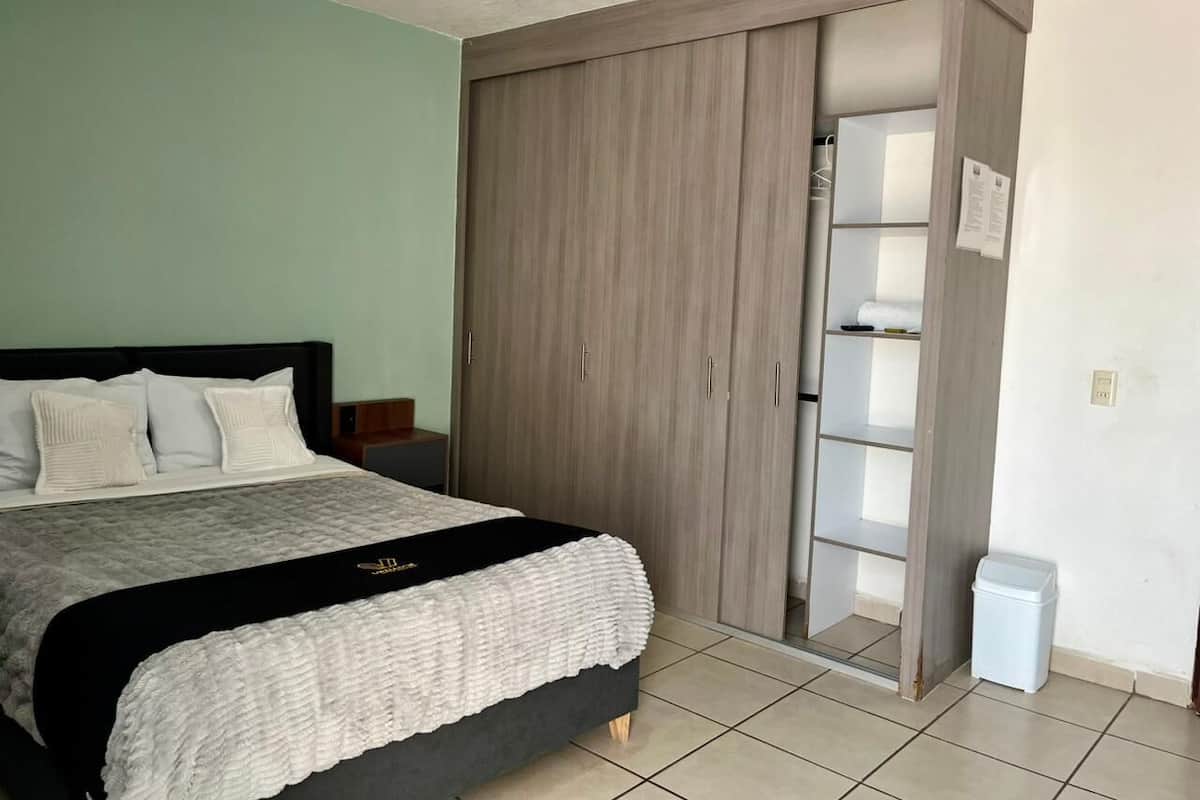 A bedroom with a bed, a wardrobe, and a small bedside table.
