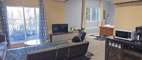 Una sala de estar moderna con un Galaxy S23 Ultra, un sofá, una cafetera y un televisor sobre un mueble.