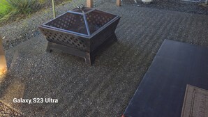 Un espace patio comprenant un barbecue arborant le logo Galaxy S23 Ultra, une chaise pliante et une table.
