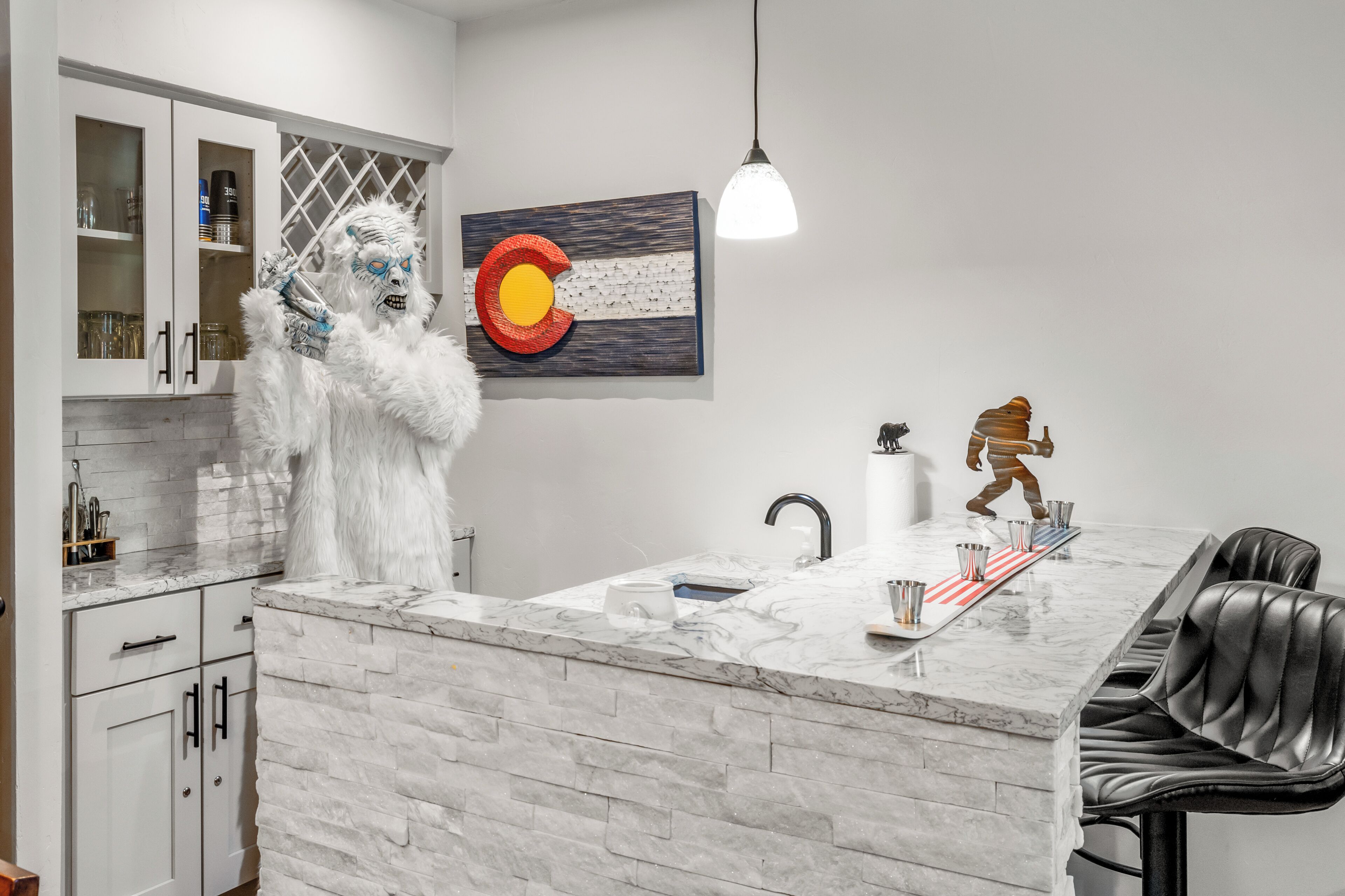 A modern kitchen with white cabinets, a marble countertop, a sink, and a decorative statue.
