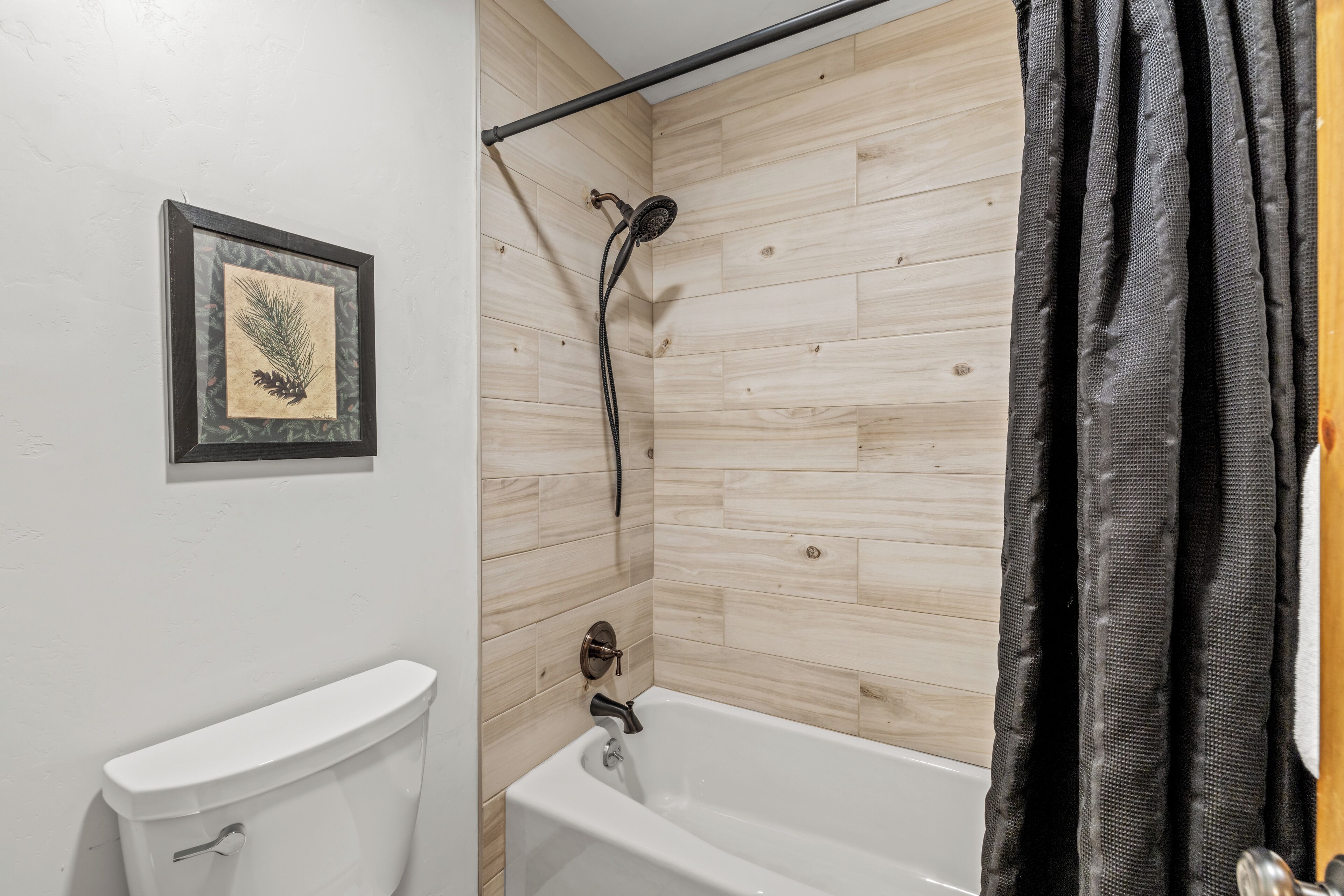 Ein Badezimmer mit Toilette, Badewanne und Dusche, dessen Wand aus Holz besteht.